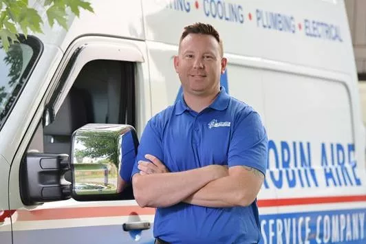 A Robin Aire HVAC technician in front of a company van