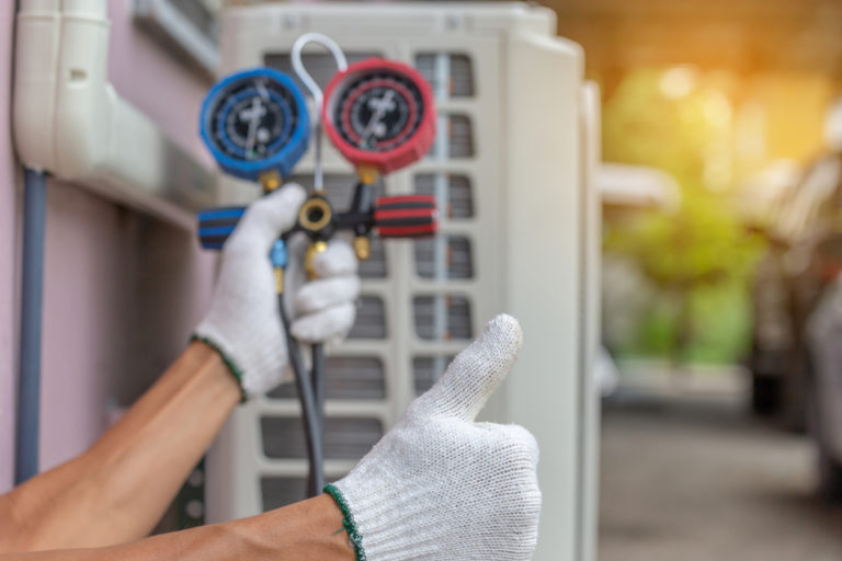 robin aire hvac tehnician holding pressure meter with white gloves on outside in garage