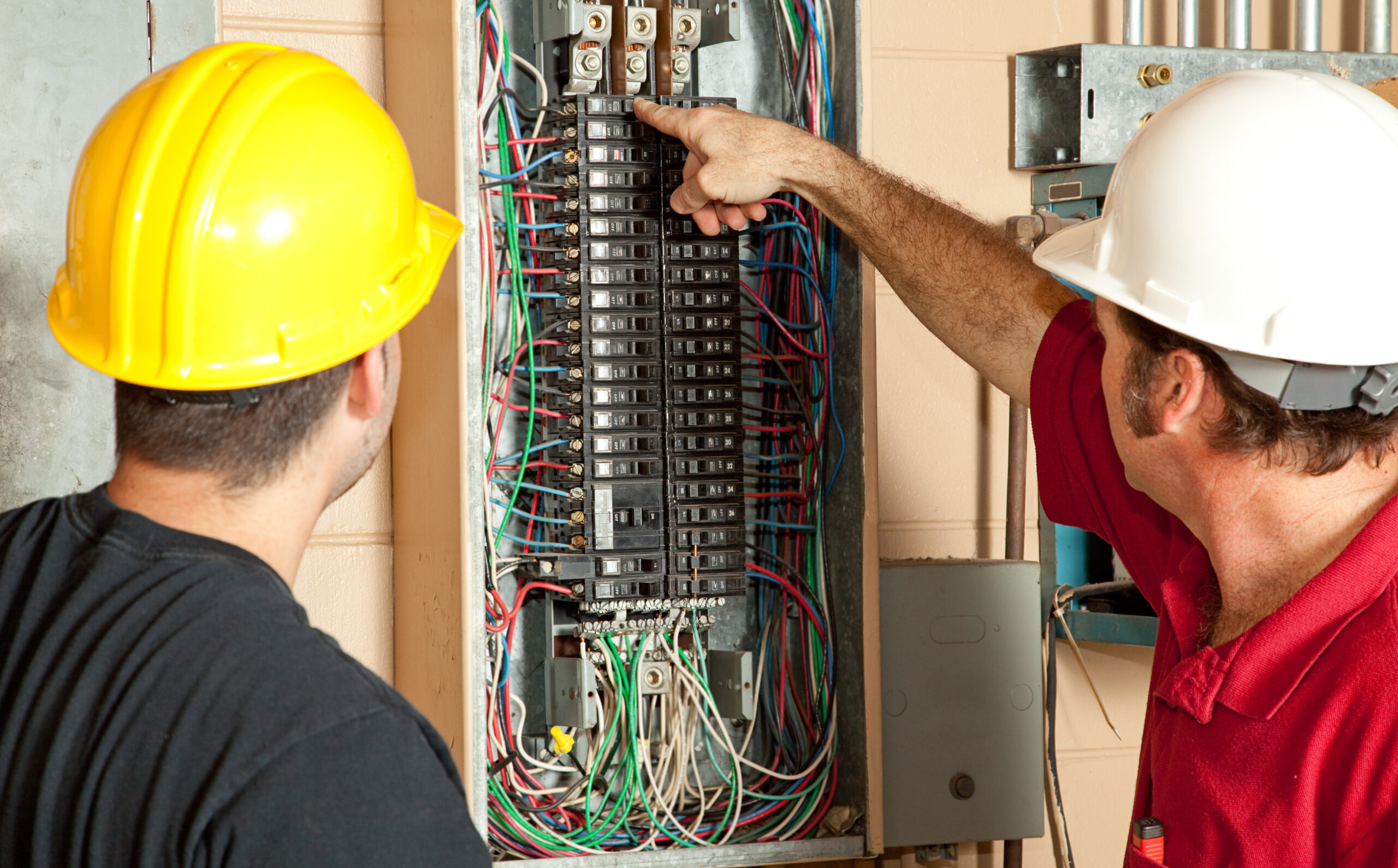 Two electricians working on a residential electrical panel in a home