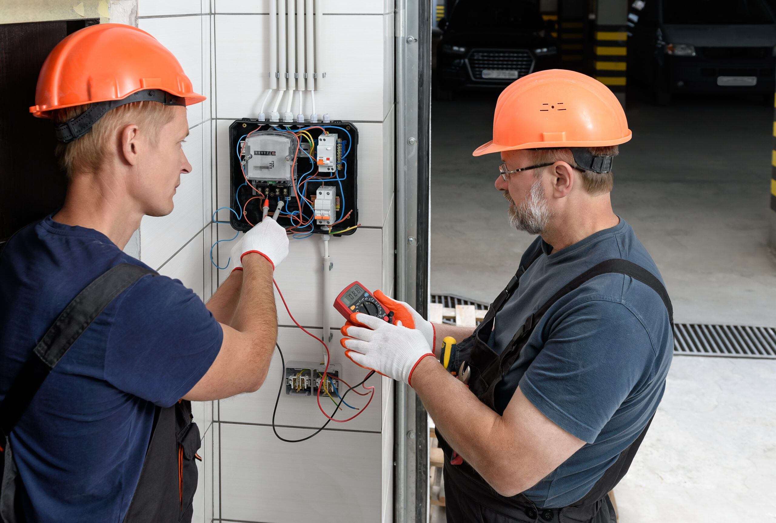 Electricians working on circuit breakers in commercial garage