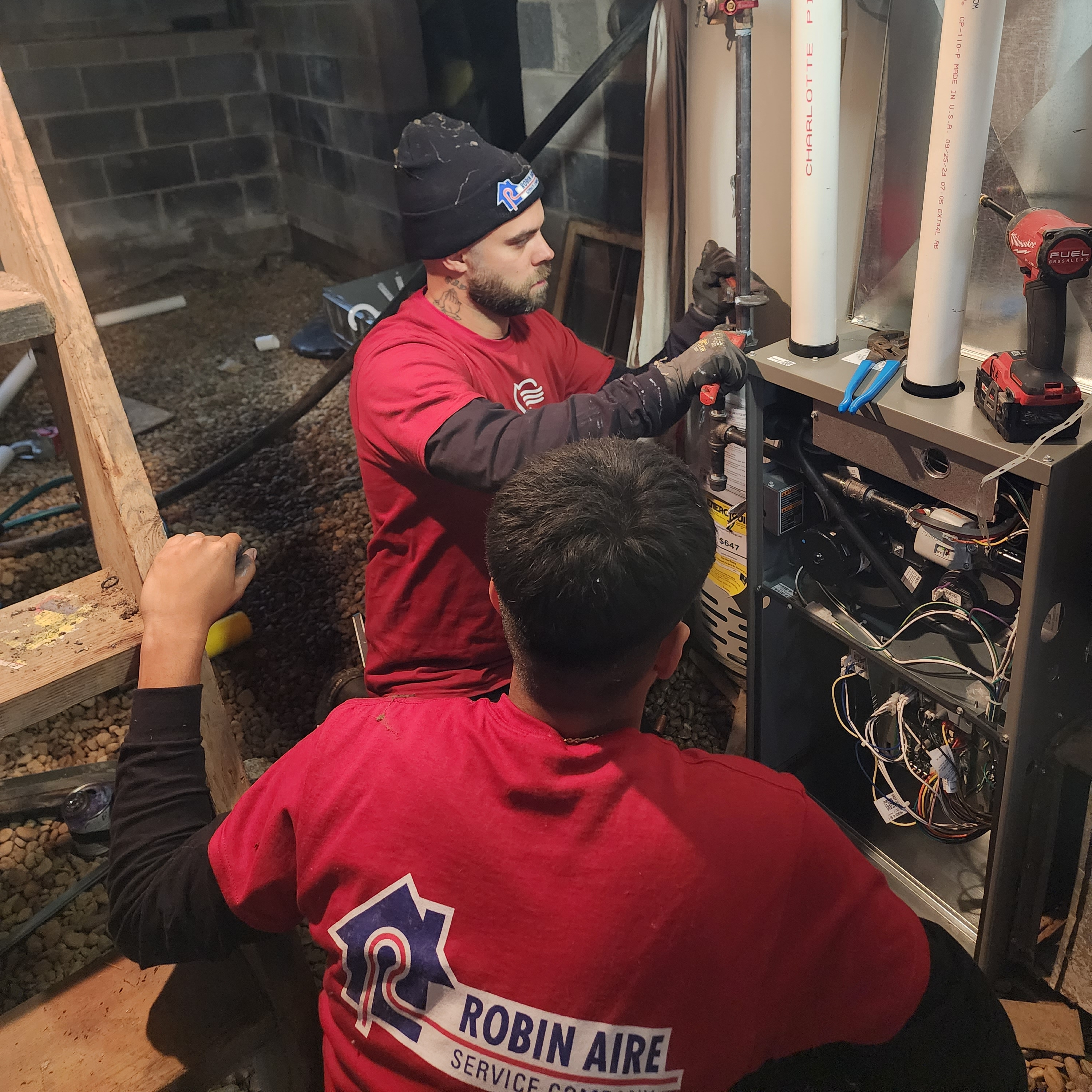 HVAC technicians installing a new unit in the basement of Feel the Love winner