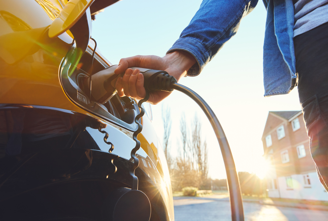 Man with his hand on the charging cord for an electric vehicle charger