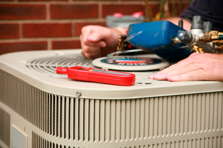Closeup of HVAC tech performing maintenance on an outdoor unit.
